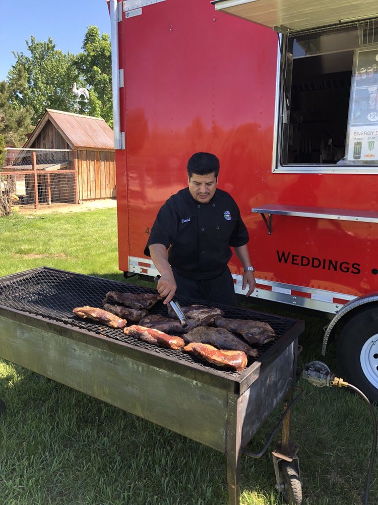 Live-fire tri-tip on the grill beside the Paisan's mobile kitchen