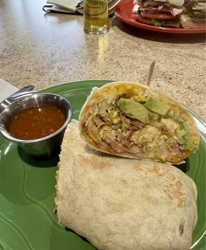 Breakfast burrito cut open: eggs, bacon, avocado, and crispy potatoes