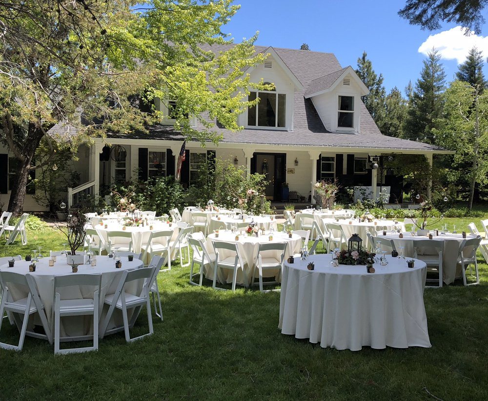 White-linen rounds set for a reception on a farmhouse lawn